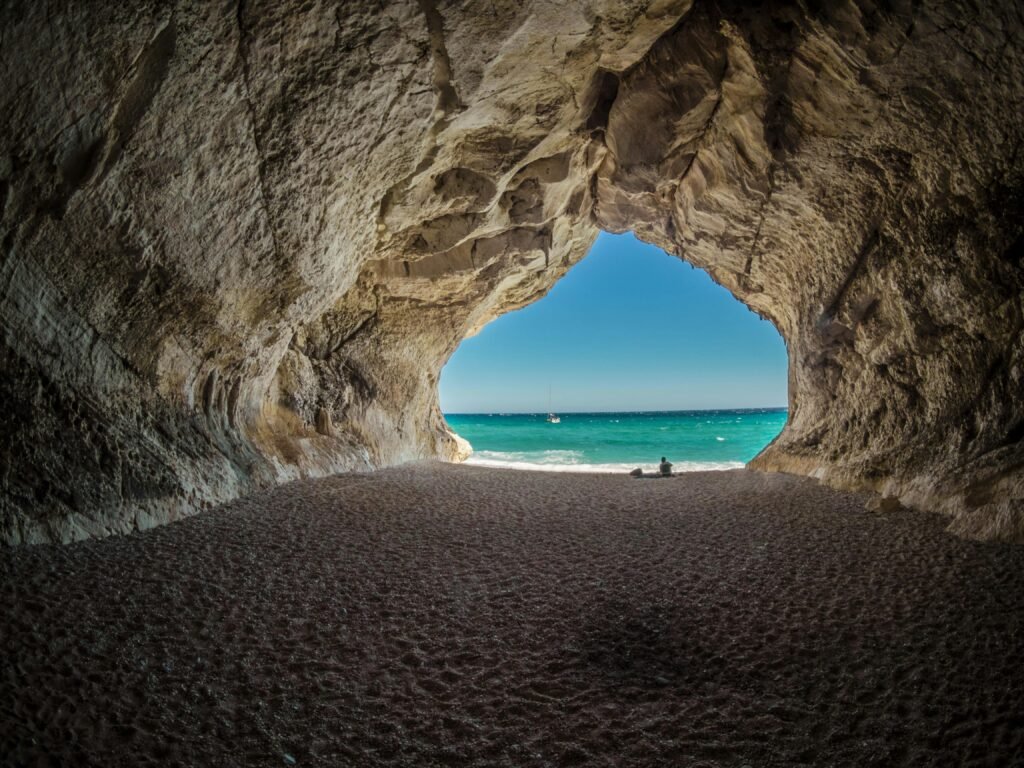 italy-cala-gonone-air-sky-163872-163872 Discover a peaceful beach scene framed by a natural cave formation, perfect for relaxation.